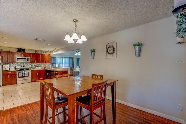 dining area featuring a textured ceiling, light wood-type flooring, and baseboards