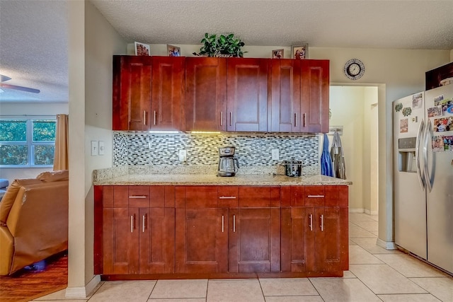 kitchen with light stone counters, a textured ceiling, tasteful backsplash, and stainless steel fridge with ice dispenser