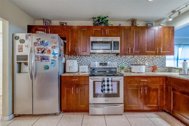 kitchen with light tile patterned floors, tasteful backsplash, a textured ceiling, and appliances with stainless steel finishes