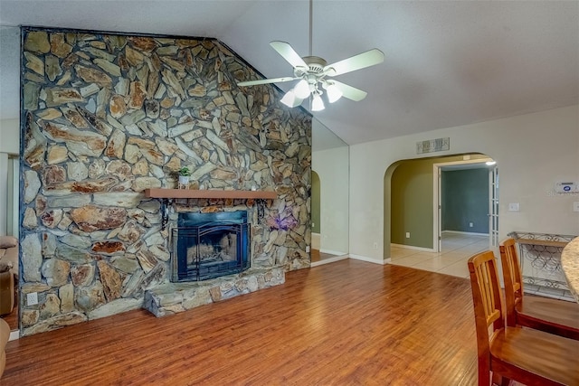 living room featuring visible vents, a ceiling fan, wood finished floors, arched walkways, and vaulted ceiling