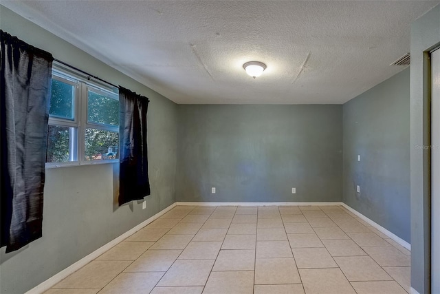 spare room with light tile patterned floors, visible vents, and baseboards