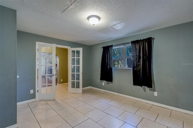 tiled spare room featuring french doors, baseboards, and a textured ceiling