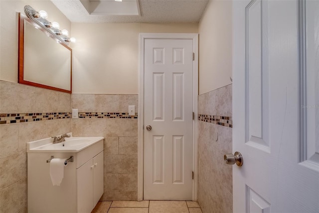 bathroom featuring a wainscoted wall, a textured ceiling, tile walls, tile patterned flooring, and vanity