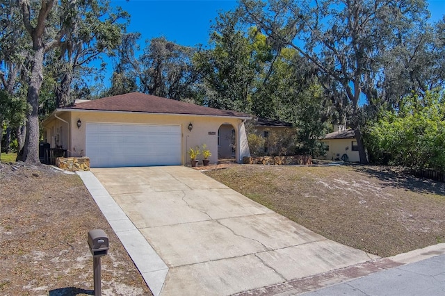 ranch-style home with stucco siding, a garage, concrete driveway, and a front lawn