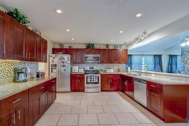 kitchen with a sink, appliances with stainless steel finishes, a peninsula, and reddish brown cabinets