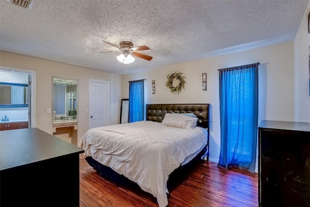 bedroom featuring visible vents, dark wood-type flooring, ensuite bathroom, a ceiling fan, and a textured ceiling