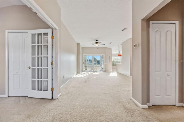 corridor with visible vents, baseboards, carpet, and a textured ceiling