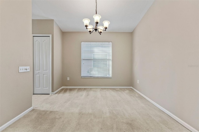 carpeted spare room with baseboards and an inviting chandelier