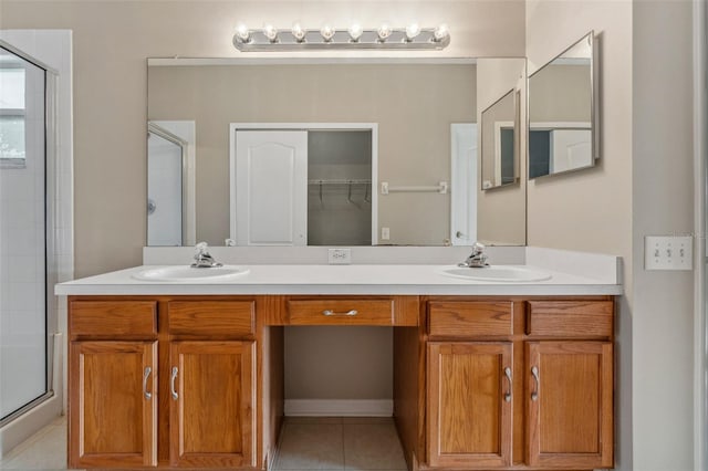 full bathroom featuring a sink, double vanity, a shower stall, and tile patterned floors