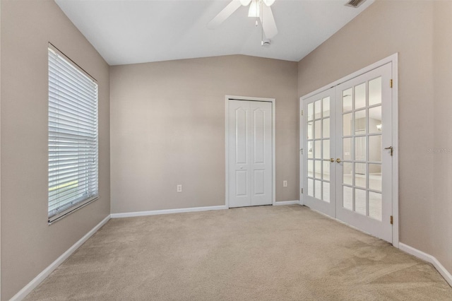 spare room with french doors, baseboards, lofted ceiling, light colored carpet, and ceiling fan