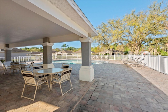 view of patio / terrace featuring outdoor dining area, fence, and a community pool