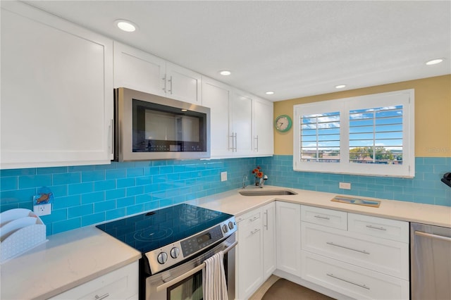 kitchen with a sink, light countertops, white cabinets, and stainless steel appliances