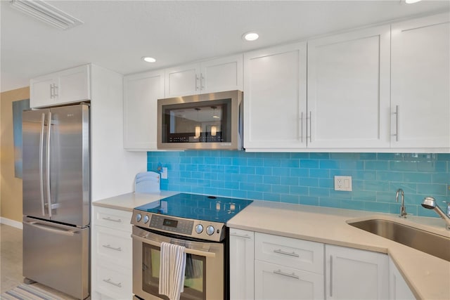 kitchen with a sink, stainless steel appliances, visible vents, and light countertops