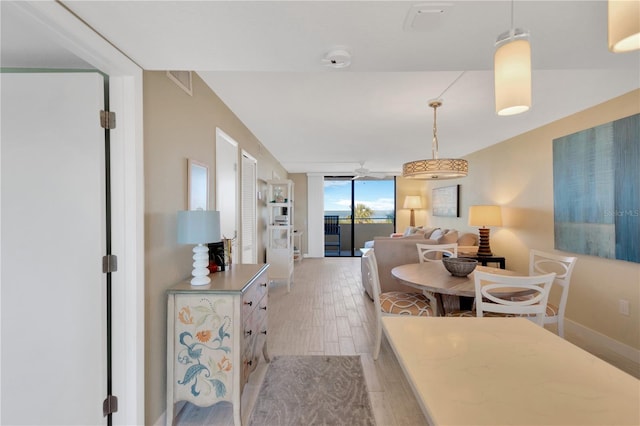 dining area with ceiling fan, baseboards, light wood-style flooring, and floor to ceiling windows