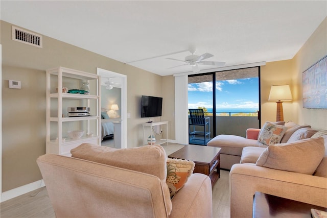 living area with visible vents, baseboards, light wood-style floors, and ceiling fan