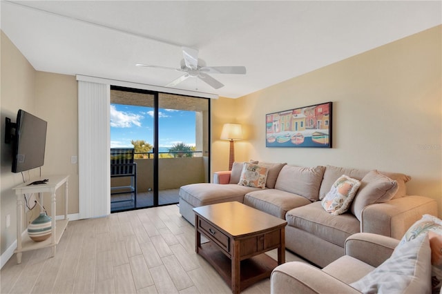 living room with a wall of windows, baseboards, light wood finished floors, and ceiling fan