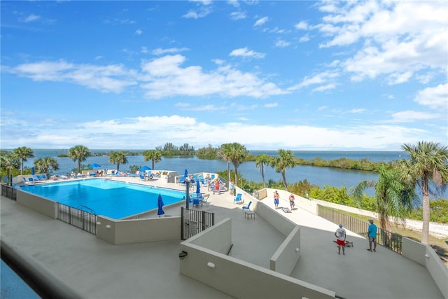 community pool with a patio area and a water view