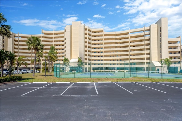 view of building exterior with uncovered parking and fence