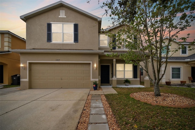 traditional-style house featuring concrete driveway, an attached garage, and stucco siding