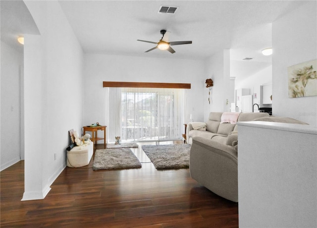 living room with ceiling fan, visible vents, baseboards, and wood finished floors