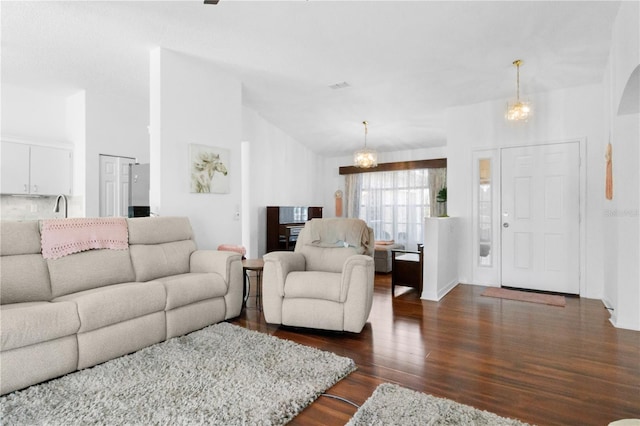 living room featuring high vaulted ceiling, an inviting chandelier, and dark wood-style floors