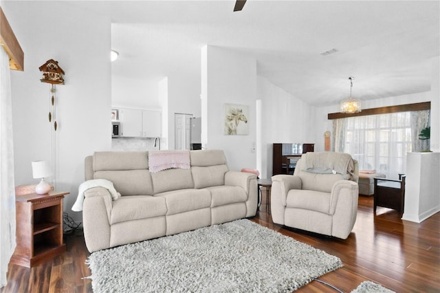 living room featuring visible vents, an inviting chandelier, dark wood-type flooring, and lofted ceiling