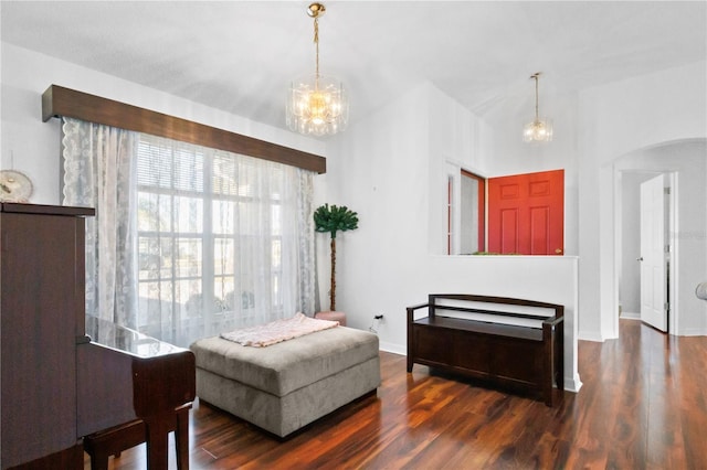 sitting room featuring baseboards, arched walkways, a notable chandelier, and wood finished floors