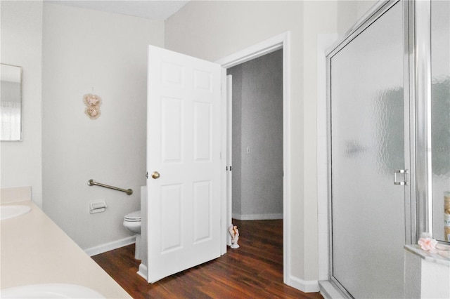 full bath with a shower stall, toilet, and wood finished floors