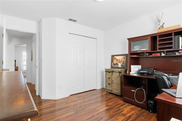 office featuring visible vents, a textured ceiling, dark wood-type flooring, and baseboards