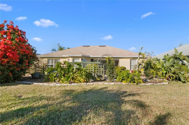 back of house with a lawn and stucco siding