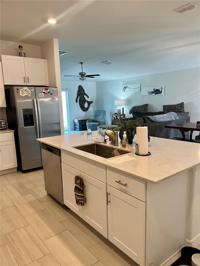 kitchen with a sink, stainless steel appliances, open floor plan, and white cabinetry