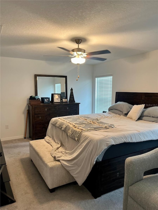 bedroom with baseboards, light colored carpet, a textured ceiling, and ceiling fan