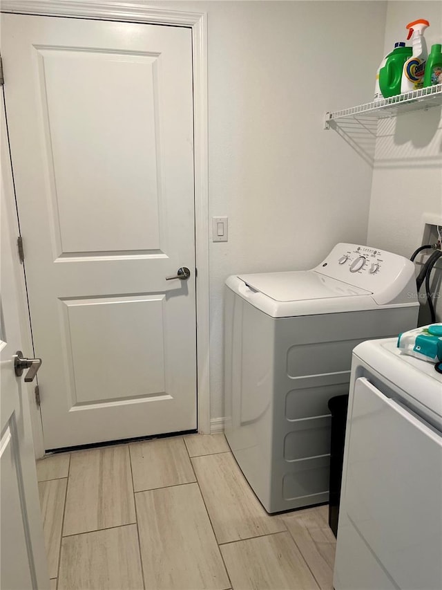 clothes washing area with laundry area, wood finish floors, and washer and clothes dryer