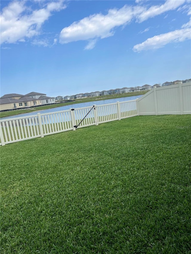 view of yard featuring a water view and a fenced backyard