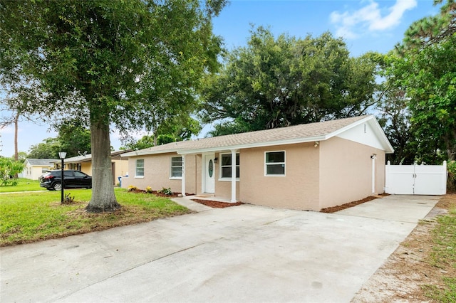 ranch-style house with a gate, fence, driveway, stucco siding, and a front lawn