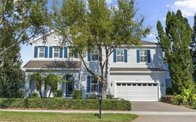 view of front of house with stucco siding, decorative driveway, and a garage