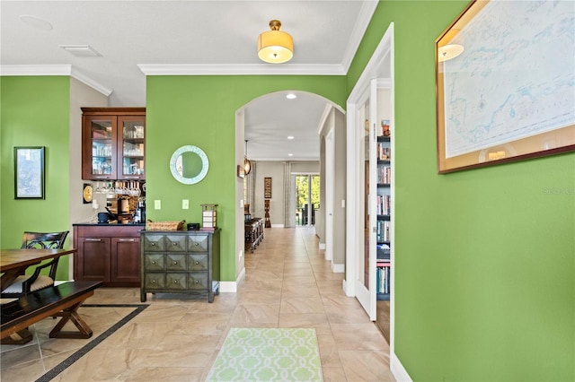 hall with arched walkways, visible vents, crown molding, and baseboards