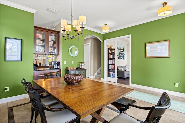 dining space with visible vents, ornamental molding, arched walkways, an inviting chandelier, and baseboards