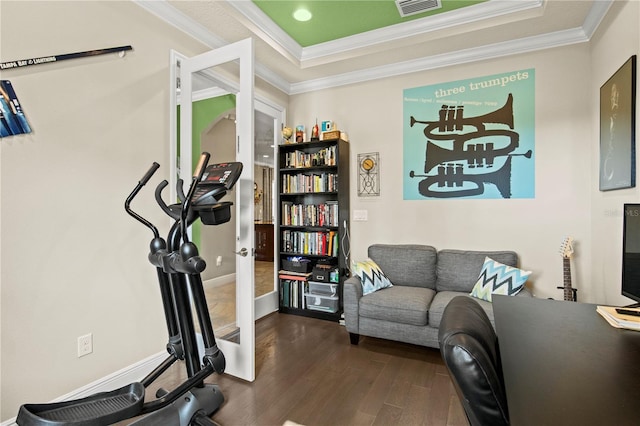 exercise room featuring wood finished floors, visible vents, baseboards, crown molding, and a raised ceiling