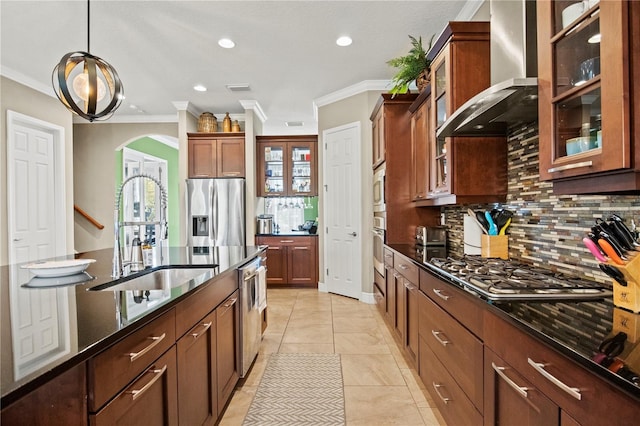 kitchen featuring backsplash, wall chimney range hood, arched walkways, stainless steel appliances, and a sink