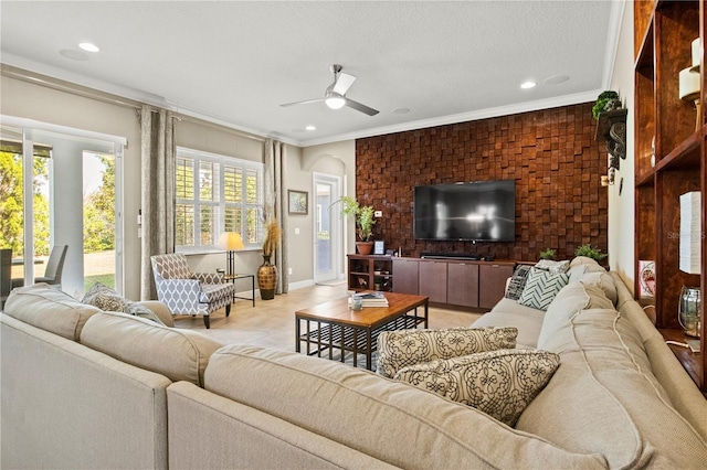 living room with a textured ceiling, baseboards, crown molding, and a ceiling fan