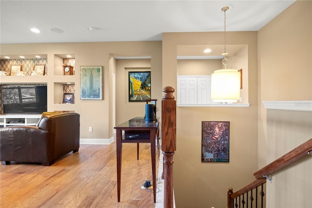 living area featuring built in shelves, wood finished floors, recessed lighting, baseboards, and stairs