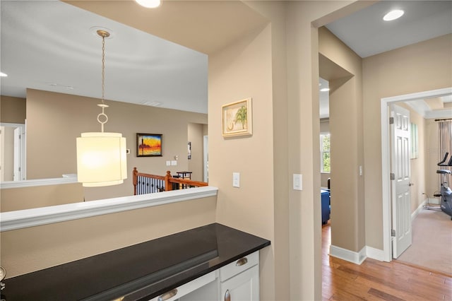 hallway with an upstairs landing, recessed lighting, light wood-style flooring, and baseboards