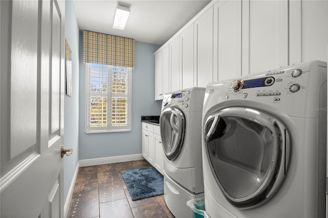 clothes washing area with baseboards, cabinet space, and washing machine and clothes dryer