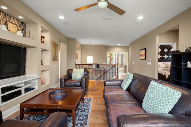 living room with visible vents, a ceiling fan, built in features, wood finished floors, and recessed lighting