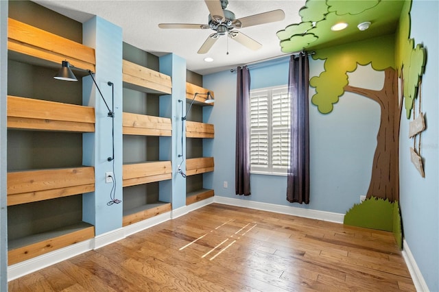 unfurnished bedroom featuring a textured ceiling, baseboards, and wood finished floors