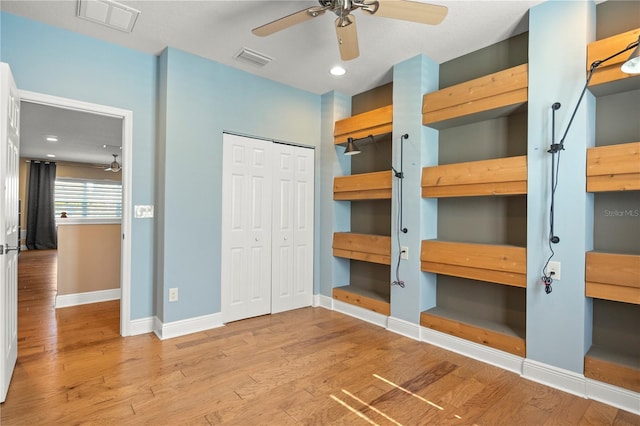 unfurnished bedroom featuring visible vents, baseboards, a closet, and wood finished floors