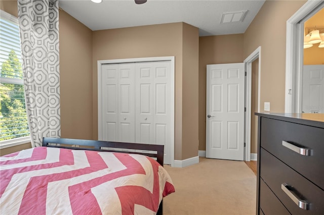 bedroom with a closet, visible vents, light colored carpet, and baseboards