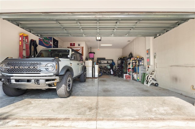 garage featuring electric panel, concrete block wall, and a garage door opener