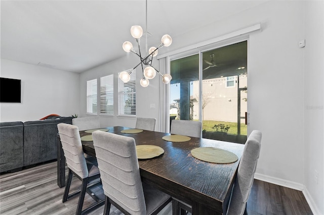 dining space featuring a chandelier, baseboards, and wood finished floors